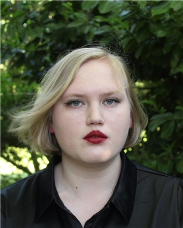 Blonde Frau guckt in die Kamera. Junge Studentin. 