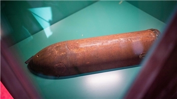 Eine Patronenhülse liegt in einer Vitrine