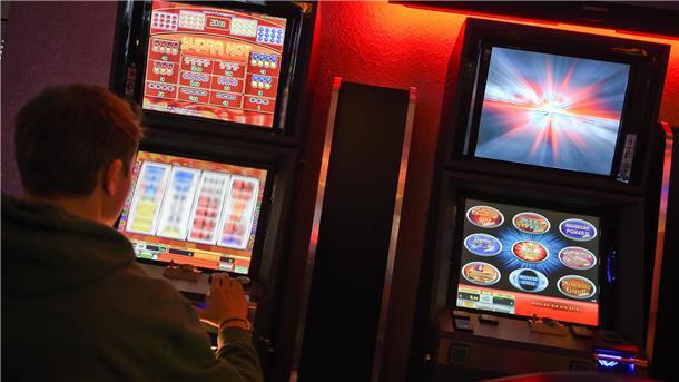 Mann sitzt vor einem Spielautomaten
