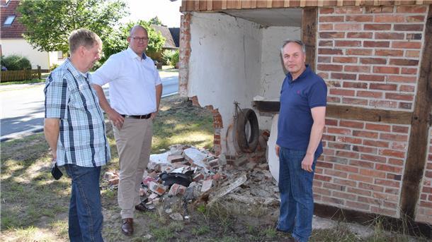 Abermals ist die Garage an der Selsinger Straße in Ostrhade beschädigt: Bürgermeister Marco Mohrmann (Mitte), sein Stellvertreter Thomas Brunckhorst (links) und Rüdiger Meyer vom „Hof Stoffers“ an der Unfallstelle.