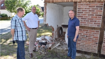 Abermals ist die Garage an der Selsinger Straße in Ostrhade beschädigt: Bürgermeister Marco Mohrmann (Mitte), sein Stellvertreter Thomas Brunckhorst (links) und Rüdiger Meyer vom „Hof Stoffers“ an der Unfallstelle.