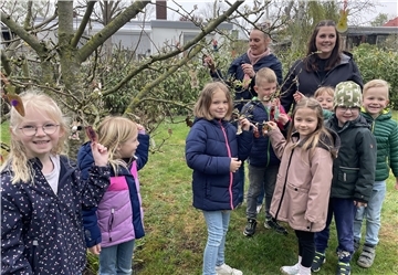 Eine Kindergartengruppe schmückt einen Baum zu Ostern.