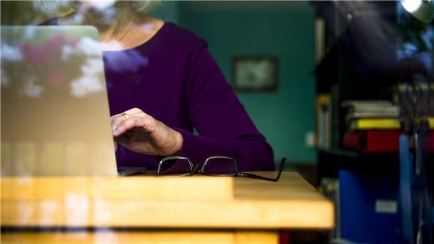 Eine Frau sitzt am Schreibtisch vor ihrem Laptop.