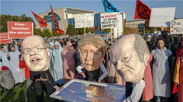Aktivisten stehen mit Masken und einem Klimapaket auf einem Silbertablett vor dem Kanzleramt.