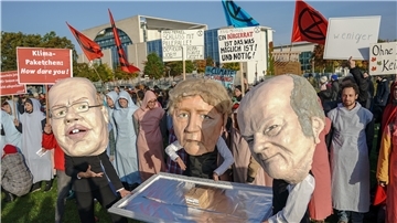 Aktivisten stehen mit Masken und einem Klimapaket auf einem Silbertablett vor dem Kanzleramt.