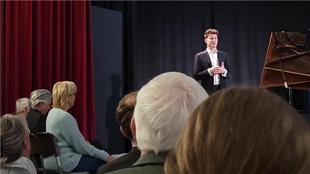 Alexander Krichel erläuterte dem Publikum die einzelnen Stücke. Zu dem Konzert waren so viele Menschen gekommen, dass auch auf der Bühne Stühle aufgestellt werden mussten.
