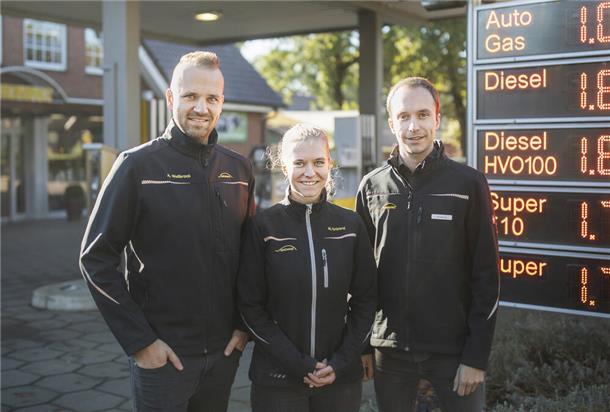 Drei junge Menschen vor einer Tankstelle.