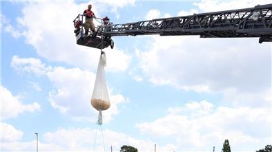 Alles bereit fürs Entenrennen: Oben Drehleiter mit Enten im Sack, unten Feuerwehrboot mit Ventilator, DLRG im Wasser.