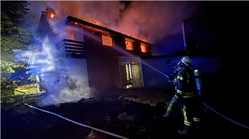 Feuerwehrleute löschen ein brennendes Haus.