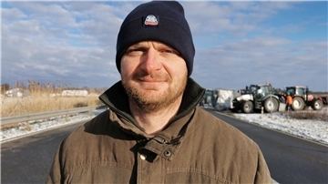 Mann mit Mütze und Winterjacke vor Traktoren im Hintergrund