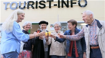 Sechs Männer und Frauen stoßen mit Gläsern an.