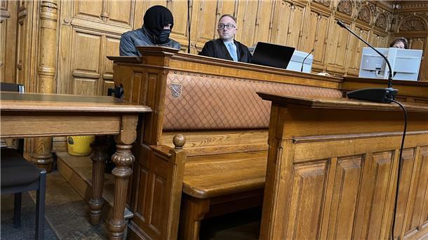 Angeklagter sitzt mit Maske neben seinem Verteidiger. 