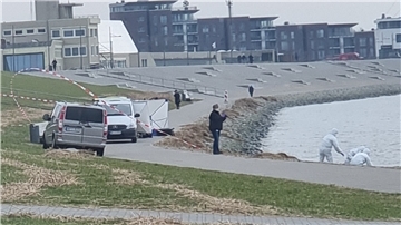 Mehrere Beamte in weißen Schutzanzügen suchen das Ufer der Weser ab.