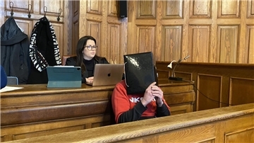 Ein Mann sitzt auf einer Bank und verdeckt sein Gesicht. 