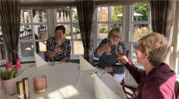 Drei Frauen stoßen mit einem Glas Wein an.