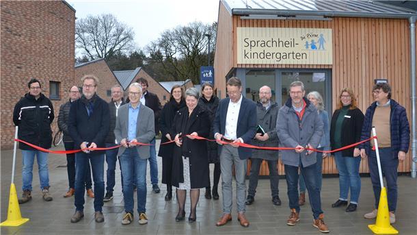 Vertreter der Stadt Zeven, der Börne und der beteiligten Firmen schneiden ein rotes Band vor dem Neubau des Sprachheilkindergartens durch.