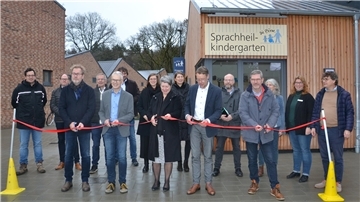 Vertreter der Stadt Zeven, der Börne und der beteiligten Firmen schneiden ein rotes Band vor dem Neubau des Sprachheilkindergartens durch.