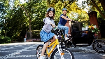 Mädchen auf Fahrrad und Frau auf Lastenrad