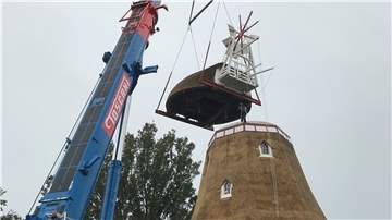 An einer Kette zieht der Dachdecker die sanierte Reetdach-Haube der Beerster Mühle an ihren ursprünglichen Platz.