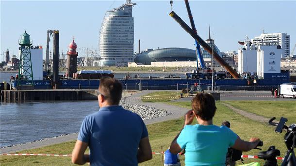 An Tag drei der Havarie, am 20. August 2022, geht der schwerlastfähige Ponton „BHV Innovation“ in der Geesteeinfahrt in Stellung. Er ist die Arbeitsbühne, auf der auch 110 Strohquader gestapelt werden, auf die der Turm fallen könnte. Jetzt versuchen die Fachleute der Bergungsfirma zu retten, was noch zu retten ist: Der Turm soll so abgetragen werden, dass später möglichst viele Teile für den Wiederaufbau wieder verwendet werden können.