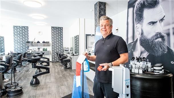 Andre Albers, Inhaber des Friseursalons „Hauptsache“ in der Bremerhavener Georgstraße, bereitet seinen Salon mit Absperrband, Desinfektionsmittelspender und Bodenleitlinien auf den Kundenansturm vor.