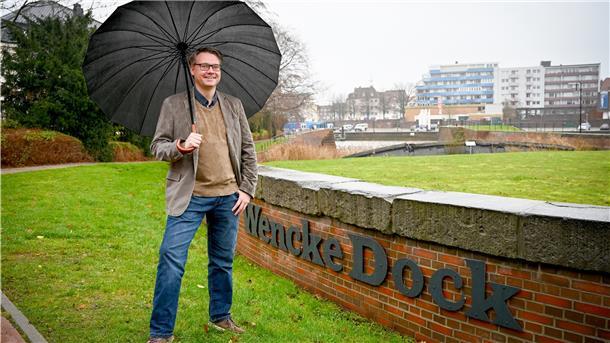 Mann mit Regenschirm auf Rasen