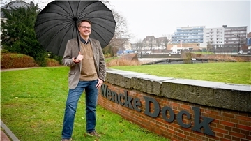Mann mit Regenschirm auf Rasen