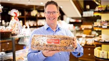 Andreas Knigge hält er einen frischen verpackten Bremer Klaben in der Hand. 