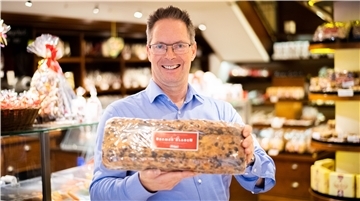 Andreas Knigge, ist neben seinem Bruder Harald, Inhaber von Café und Konditorei in der Sögestraße. In den Händen hält er einen frischen verpackten Klaben.