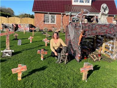Frau mit Hund im Garten mit vielen Holzkreuzen