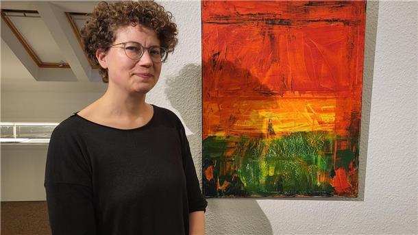 Eine Frau mit Brille und Locken vor einem 