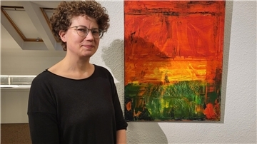 Eine Frau mit Brille und Locken vor einem 