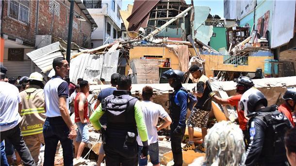 Anwohner und Rettungskräfte stehen vor zerstörten Gebäuden in Machala.