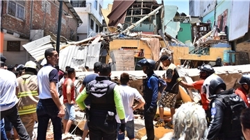Anwohner und Rettungskräfte stehen vor zerstörten Gebäuden in Machala.