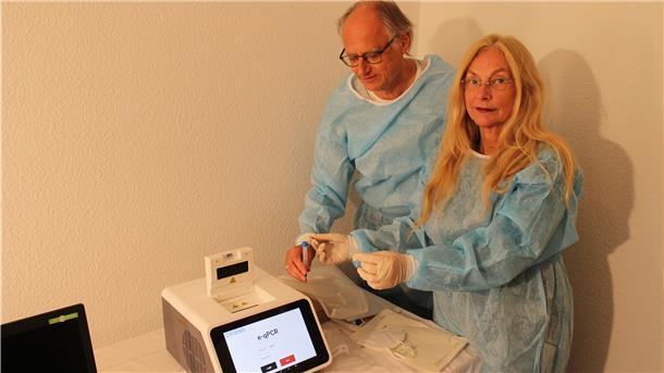 Apotheker Dr. Andreas Völsch und seine Frau Bärbel zeigen für unser Foto, wie das neue PCR-Testgerät funktioniert.