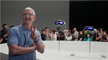 Apple-CEO Tim Cook posiert neben den neuen Vision Pro Headsets auf dem Firmencampus in Cupertino.