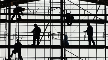 Arbeiter montieren auf einem Gerüst die Glasfassade des Bahnhofs von Frankfurt am Main.