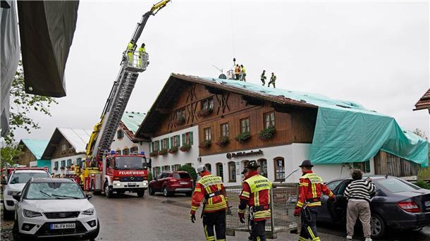 Arbeiter und Feuerwehrleute beseitigen die Unwetter-Schäden im oberbayerischen Bad Bayersoien. Bei dem Unwetter wurden viele Dächer beschädigt.