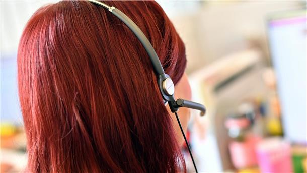 Eine Frau mit Headset telefoniert.