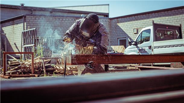 Auch an heißen Tagen schweißt Metallbauer Marcel Buck Metall unter Schutzgas mit voller Sicherheitsausrüstung. Doch er ist nicht der Einzige, der bei der Arbeit besonders schwitzt.