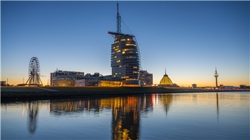 Das ATLANTIC Hotel Sail City spiegelt sich bei Sonnenaufgang im Wasser.