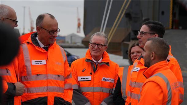 Bundeskanzler Friedrich Merz spricht im Bremerhavener Hafen mit einem Mitarbeiter.