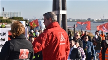 Auch der Bundestagsabgeordnete aus Bremerhaven, Uwe Schmidt (SPD, hier im Hintergrund am Rednerpult), hat es zur Demonstration der IG Metall am Blexer Fähranleger auf die andere Seite der Weser geschafft.