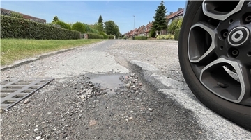 Autoreifen neben einem Schlagloch.