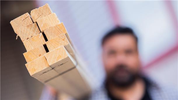 Demografischer Wandel verschärft Suche nach Fachkräften Ein Dachdecker hält Dachlatten aus Holz.