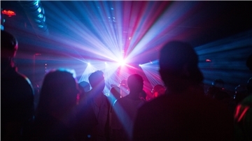 Tanzende Menschen in grellem Licht der Club-Atmosphäre.
