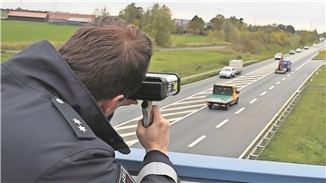 Ein Polizist kontrolliert auf der B212 in der Wesermarsch die Geschwindigkeit von Fahrzeugen.
