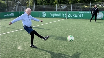 Dr. Reinhard Krause schießt einen Fußball.