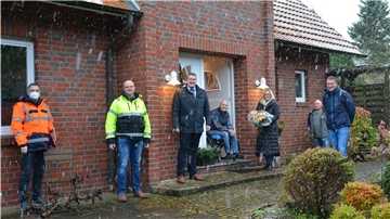 Menschen stehen vor einem Haus. 