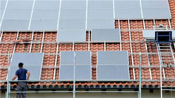Ein Arbeiter montiert Solarmodule auf einem Dach